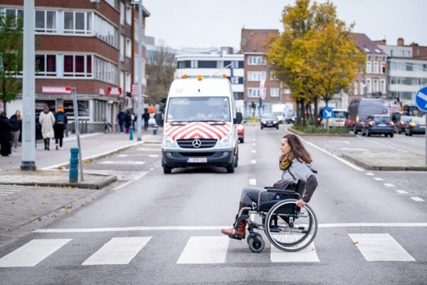 vrouw in rolstoel op zebrapad
