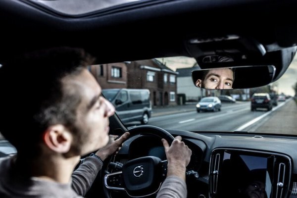 man die in achteruitkijkspiegel kijkt tijdens het rijden