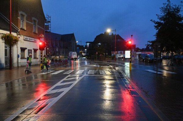 voetgangers in de regen wachten bij verkeerslicht