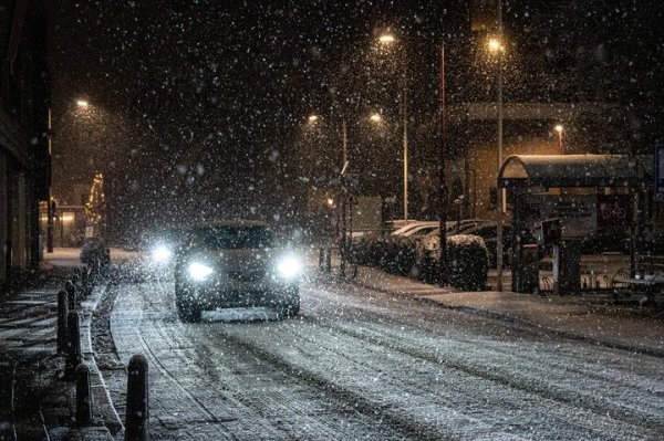 auto rijdend in het donker bij sneeuwval