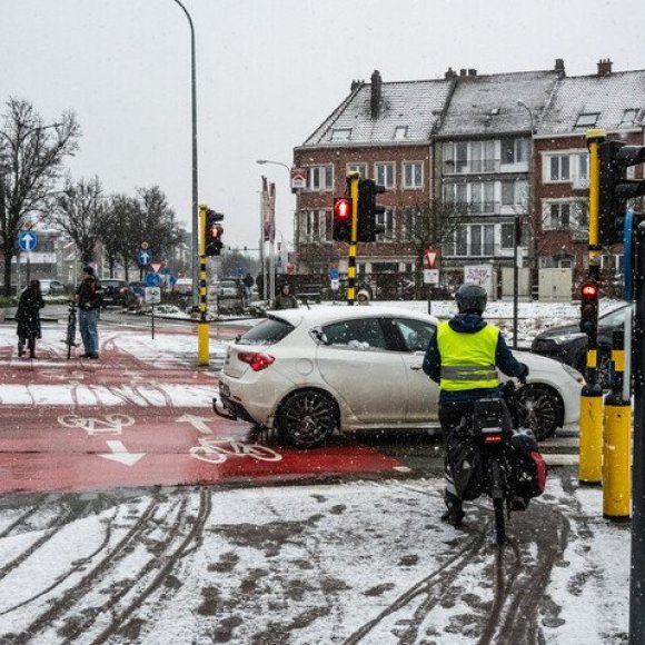 Fietser aan kruispunt met verkeerslichten bij sneeuwval