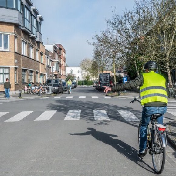 fietser steekt arm uit om links af te slaan op kruispunt