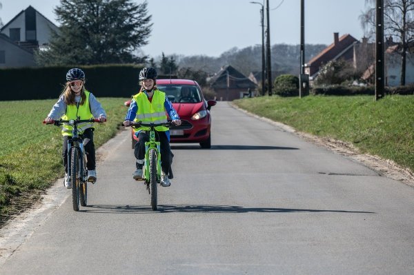 2 kinderen die naast elkaar op de rijbaan fietsen